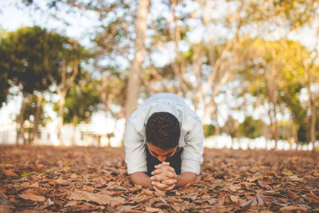 Man kneeling on leaves, praying