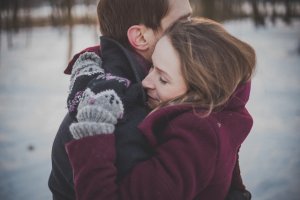 Couple hugging in snowy field