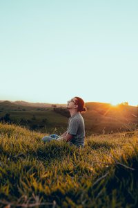 Peaceful man sitting in a field with a sunset